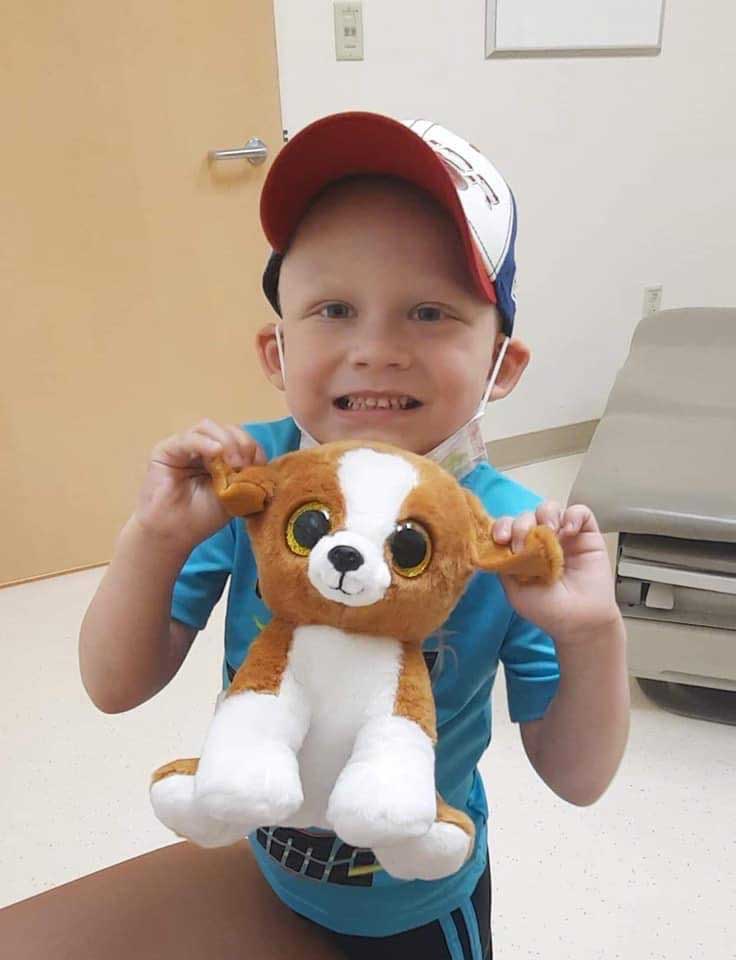 Rylan, a brave young boy with high-risk neuroblastoma holding his favorite stuffed teddy bear.