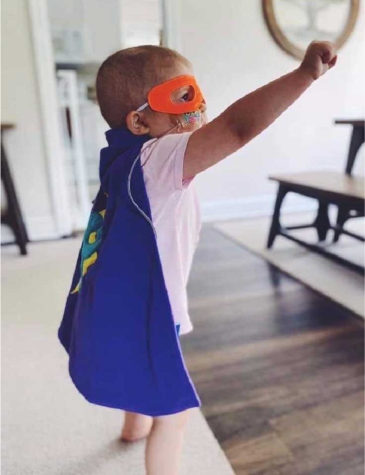 Preslie, a super-strong 4-year-old undergoing treatment at Children's Hospital, in Milwaukee Wisconsin poses with a fist toward the sky like a superhero.